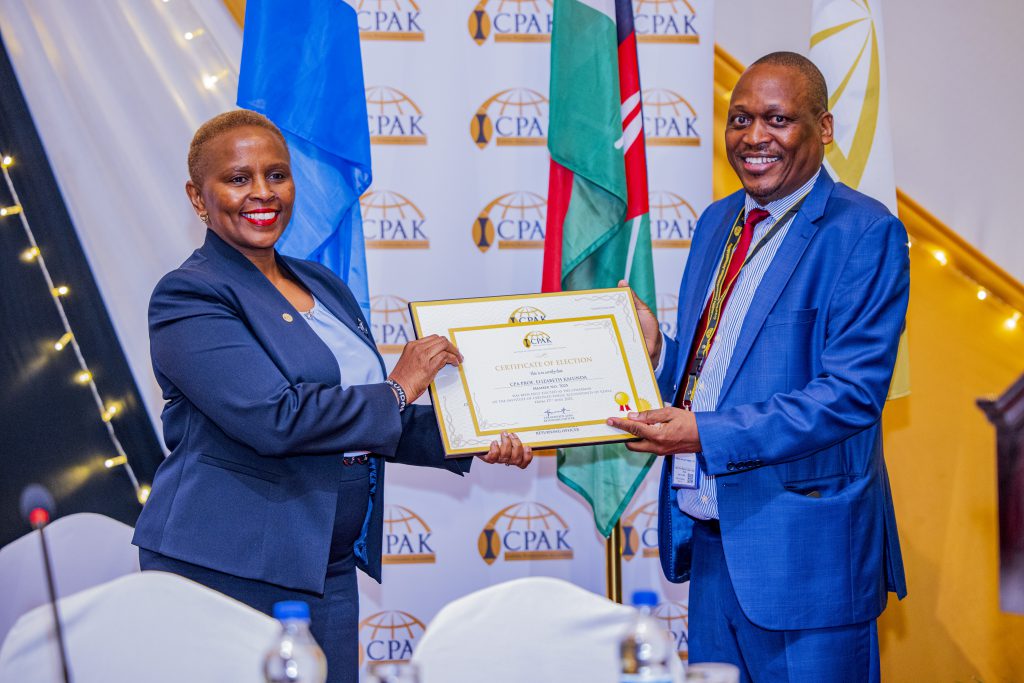 ICPAK council elections returning Officer CPA Kennedy Auka presenting a certificate of Election to the 26th ICPAK chairman CPA Prof. Elizabeth Kalunda